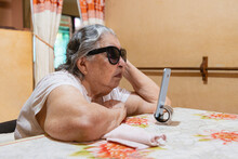 Elderly blind woman using cell phone. 
