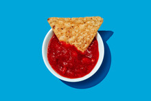 Tortilla Chip In A Bowl With Some Tomato-based Salsa