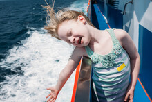 A Little Girl Leans Over The Edge Of A Boat