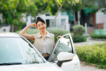 Beautiful young asian woman standing next to her car and smiling