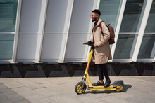 A young businessman goes to work on an electric scooter