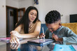 © Pedro Merino/Stocksy - Girl babysitting a primary school boy doing his homework with a tablet