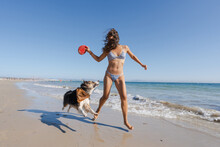 Woman Playing On The Beach With Her Dog