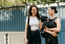 Two Young Women Petting Their Little Dog In Pris France. 