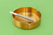 © Kristen Angelo/Stocksy - Cannabis preroll joint in a round gold ashtray
