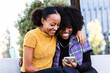 © VICTOR TORRES/Stocksy - Cheerful girlfriends using smartphone on street