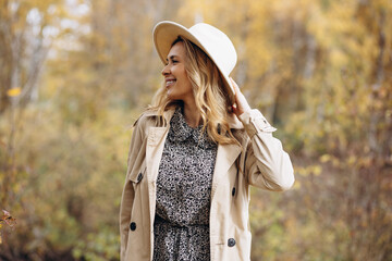 beautiful woman wearing a hat and coat walking in autumn park