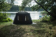 Namiot rozłożony nad brzegiem jeziora w słoneczny dzień.