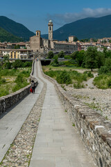 The ancient Ponte Gobbo over the Trebbia river with Bobbio in the background, Italy