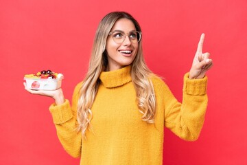 Canvas Print - Young pretty Uruguayan woman holding a bowl of fruit isolated on red background pointing up a great idea