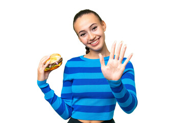 Wall Mural - Young Arab woman holding a burger over isolated background counting five with fingers