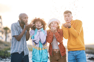 Wall Mural - Friends, outdoor and people blowing confetti outdoor for celebration, motivation and fun. Diversity, happiness and group of men and women for adventure, party and happy youth with freedom in nature