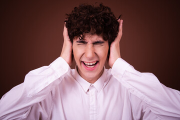 Wall Mural - Funny young guy posing in the studio on a brown background.