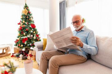 Wall Mural - Senior man reading newspapers at home on Christmas morning