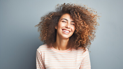 Portrait of beautiful young woman with curly hair smiling. Emotion concept.
