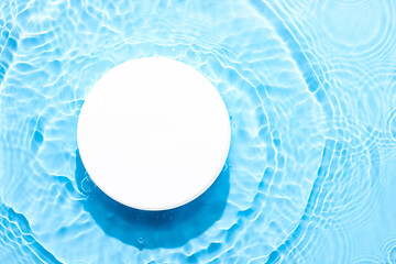 Water blue surface abstract background. Waves and ripples texture of cosmetic aqua moisturizer with bubbles and white product pedestal.