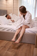 © Svitlana - Woman sitting on bed and looking at sleeping man