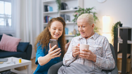 A nurse is assisting a senior woman in making a video call to her relatives as part of her volunteering efforts