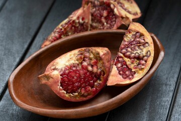 Sticker - Fresh pomegranate halves on a rustic wooden plate, against a dark background