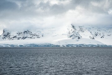 Canvas Print - Aerial view of a mountainous terrain covered in a gleaming blanket of fresh white snow in Antarctica