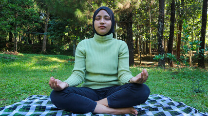 Wall Mural - Portrait of peaceful muslim woman training and meditation with closed eyes. Practicing of yoga.