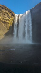 Canvas Print - Stunning landscape of a majestic waterfall surrounded by an expanse of dry, golden grass