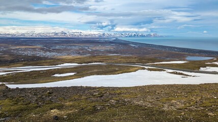 Poster - Tranquil landscape featuring a snow-covered field with a small lake in the background