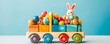 Colorful toy truck loaded with colorful Easter eggs and a happy bunny on blue background with copy space.