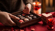 A close-up of hands exchanging chocolates and candies from an elegantly decorated gift box, showcasing indulgence and affection. 