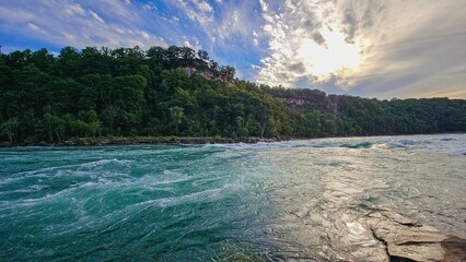 Sticker - the sun is setting in the distance over a river and a cliff