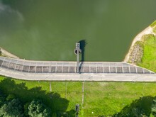 Drone View Of A Concrete Hydroelectric Dam With A Pump Station Situated On A Serene Lake