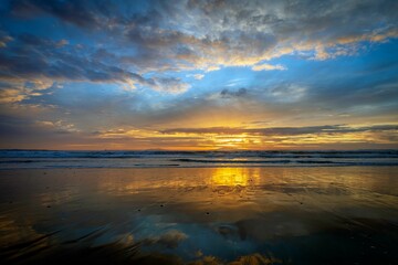 Canvas Print - Calm ocean during the low tide in Oxnard California with the golden sunset shining in the background