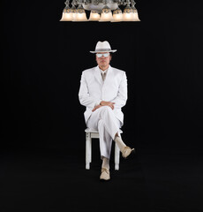 Sticker - rich gentleman in a white suit sits on a chair, black studio background