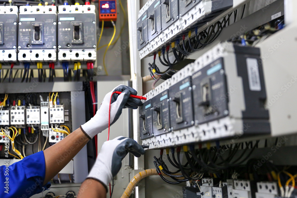 Electricity and electrical safety maintenance service system, Technician hand checking electric current voltage at circuit breaker terminal and cable wiring in main power distribution board.