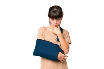 Wall Mural - Little caucasian girl with broken arm and wearing a sling over isolated background thinking