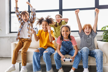 Wall Mural - Group of joyful teenage friends with joysticks enthusiastically playing game console  .