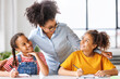 © JenkoAtaman - African american teacher smiling and helps students during lesson in bright classroom .