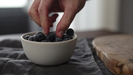 Wall Mural - Slow motion man take washed blueberries from white bowl on table