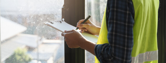 Asian inspector checking structure of new property and taking note in the clipboard for review and fix the house before sell to client