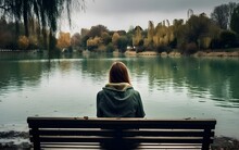 Depressed And Sad Young Woman With Long Hair Casual Clothes Sitting Alone On Bench In The Park, Back View, Looking At Lake City Landscape, In Deep Thoughts, Sadness, Mist, Autumn, Winter, AI Generated