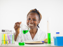  Young Female Scientist Keenly Observing A Sample In An Erlenmeyer Flask Inside A Laboratory Looking At Camera