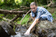 © Wosunan - Hiker in the jungle playing with water in a stream in the forest.