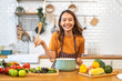 © Art_Photo - Young woman standing near stove and cooking, housewife, meal, chef, food.Happy woman looking and smelling tasting fresh delicious from soup in a pot with steam at white interior kitchen