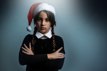 Wall Mural - Portrait of little girl with Wednesday costume. Wednesday girl with a Santa hat