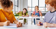 © JenkoAtaman - Cheerful kids schoolchildren laughing while sitting at their desks at school