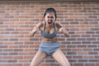 Anger Asian Girl In Gray Shorts On Brick Wall Background