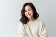Medium shot portrait of a Chinese woman in her 20s in a white background wearing a cozy sweater