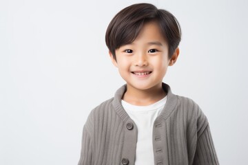 Wall Mural - Lifestyle portrait of a Chinese child male in a white background wearing a chic cardigan