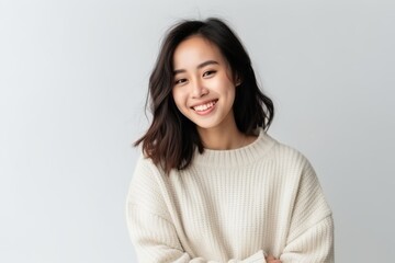 Wall Mural - Medium shot portrait of a Chinese woman in her 20s in a white background wearing a cozy sweater