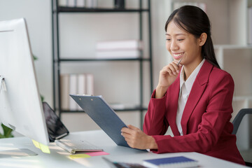 Poster - Confident Asian businesswoman sitting on desk in office